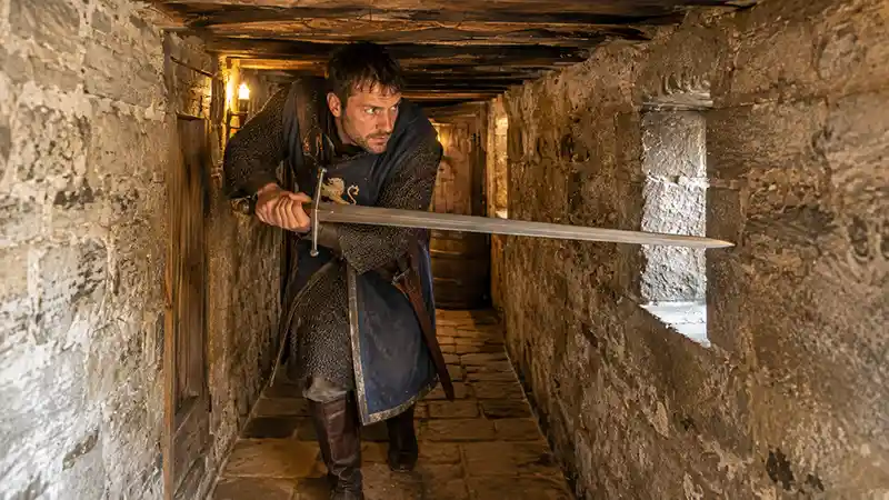 Warrior maneuvering a long sword through a narrow stone corridor
