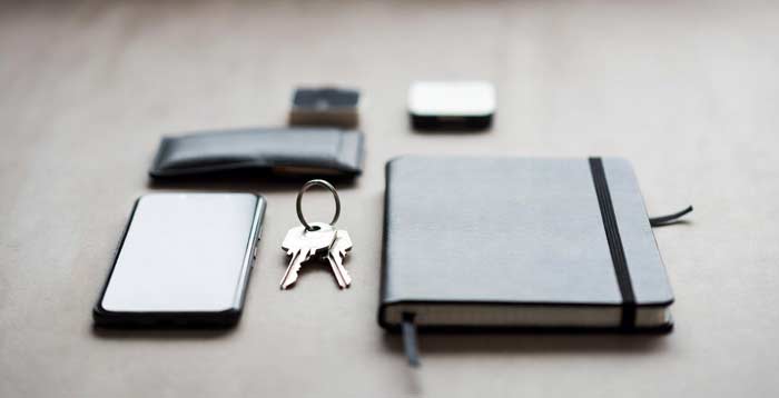 Flat lay of everyday items like phone, keys, wallet, and notebook arranged to represent decision making and daily carry