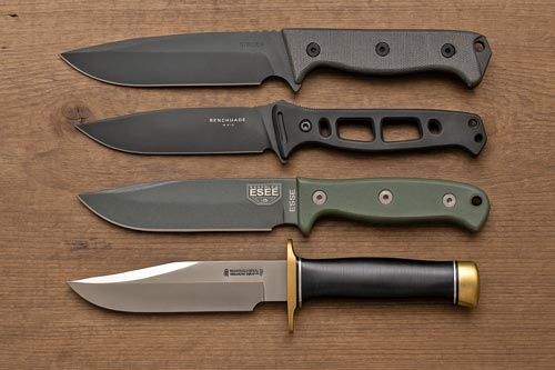 Four modern tactical fixed blade knives arranged on a wooden surface